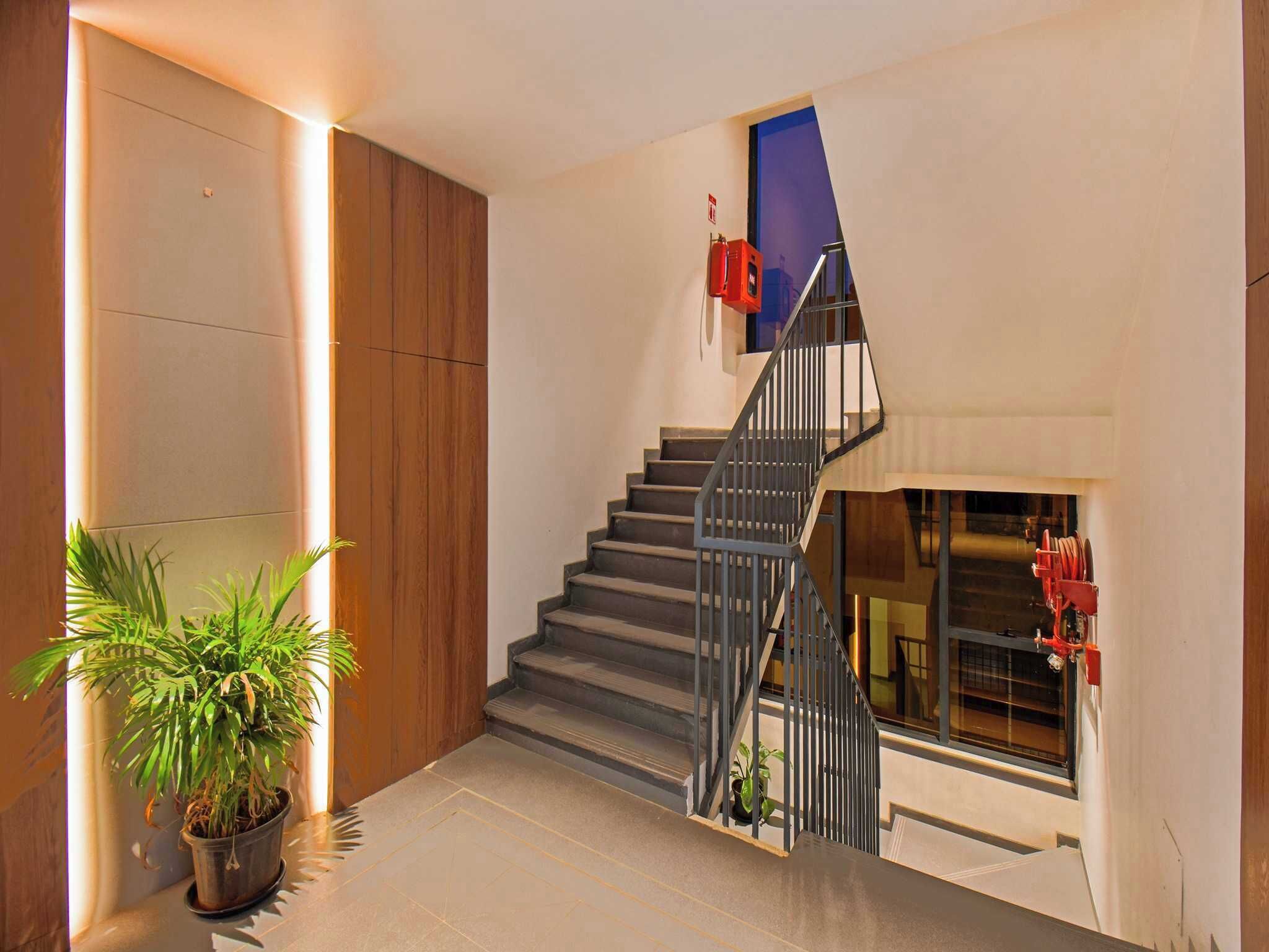 A modern staircase with a metal railing, a potted plant, and a fire extinguisher on the wall.