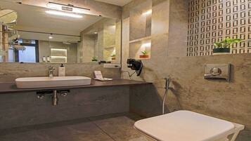 Une salle de bain moderne avec un grand miroir, deux vasques, des toilettes et une douche.
