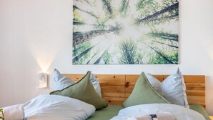 A neatly made bed with pillows, a wooden headboard, and a wall-mounted picture of a forest. - Panoramic Lake House at Steinhuder Meer – Your Exclusive Retreat by the Water (Wunstorf)