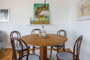 A dining area with a round wooden table, four chairs, a hanging lamp, and two framed artworks on the wall. - Panoramic Lake House at Steinhuder Meer – Your Exclusive Retreat by the Water (Wunstorf)
