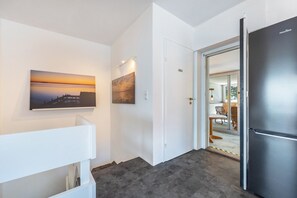 A hallway with a refrigerator, a door leading to a dining area, and two paintings on the wall. - Panoramic Lake House at Steinhuder Meer – Your Exclusive Retreat by the Water (Wunstorf)