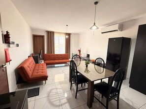 Eine moderne Küche mit Esstisch, Stühlen, einer Couch und einem Kühlschrank.