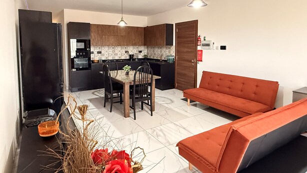 Une cuisine moderne avec un coin repas, un canapé et une plante décorative.
