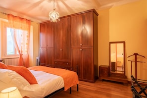 Een slaapkamer met een bed, een kledingkast, een spiegel en een hangstoel.
