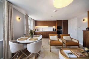 Une cuisine moderne avec des meubles en bois, un four encastré et un coin repas comprenant une table ronde et des chaises.