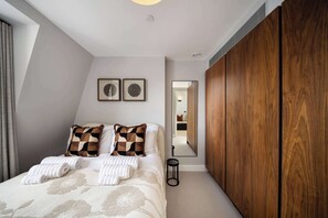 Une chambre à coucher avec un lit, deux oreillers, une table de chevet, un miroir et une armoire.