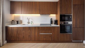 Una cocina moderna con armarios de madera, un lavamanos de acero inoxidable, un microondas Bosch y un horno.