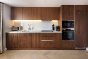 A modern kitchen with wooden cabinets, a stainless steel sink, a Bosch microwave, and an oven. - 6 Mins Walk to Selfridges, Marble Arch Penthouse (Greater London)