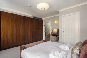 A bedroom with a large bed, a wardrobe, a desk with a chair, and a door. - 6 Mins Walk to Selfridges, Marble Arch Penthouse (Greater London)