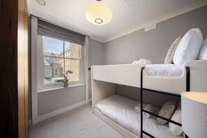 A bunk bed with a window view of buildings, a small table with a plant, and a ceiling light fixture. - 6 Mins Walk to Selfridges, Marble Arch Penthouse (Greater London)