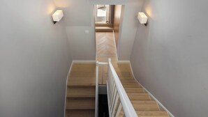 Una escalera de madera con barandillas blancas que conduce a una habitación con piso de espiga.