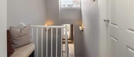 A hallway with a bench, a staircase, and a door.