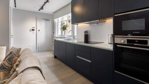 A modern kitchen with dark cabinetry, a built-in oven, and a window overlooking the street. - 9 Mins Walk to Selfridges, Marble Arch Studio (Greater London)