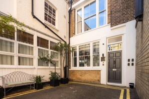 A residential property with a front door, windows, and a small garden area with a bench and potted plants. - 8 Mins Walk to Selfridges, Marble Arch Mews (Greater London)