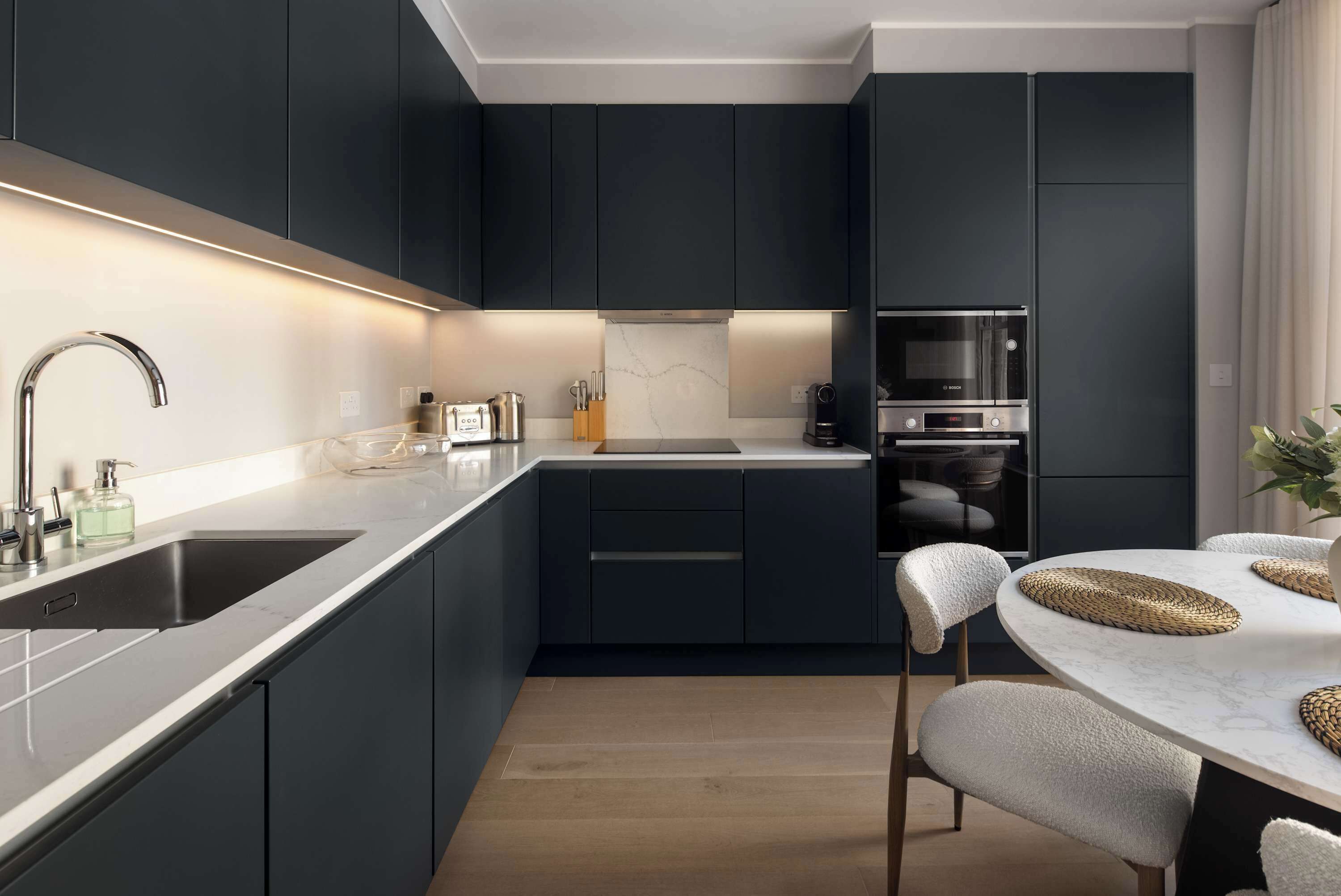 Une cuisine moderne avec des meubles de couleur sombre, un évier en acier inoxydable et un four Bosch.