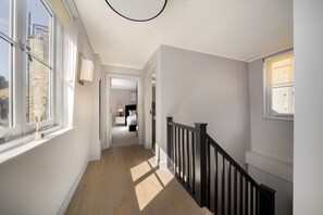 Ein Flur mit Treppe, einem Bett und einem Nachttisch im Hintergrund.