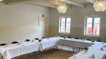 Un salón de conferencias con mesas largas, manteles blancos y modernos candelabros de cristal.