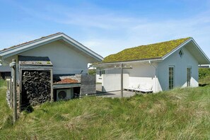 A modern house with a sloped roof, a stone wall, and a small porch. - Summer cottage with grass roof in Klitmøller (Thisted)