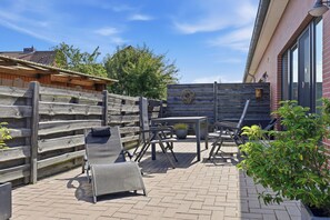 A patio with outdoor furniture, a wooden fence, and a brick wall. - To the Ankerplatz: A vacation near Greetsiel with a large terrace (Greetsiel)