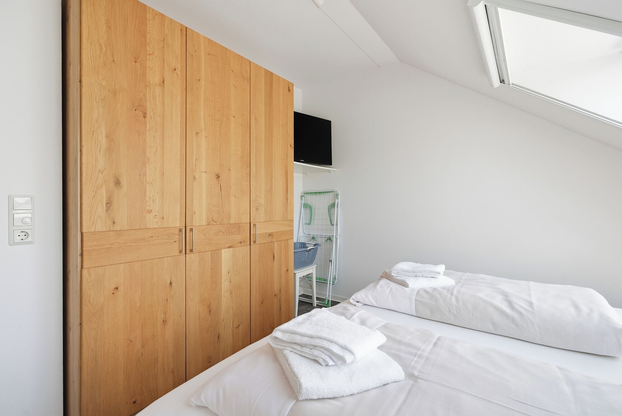 Una camera da letto con un'armadiatura in legno, un letto con lenzuola bianche e una lampada a soffitto.