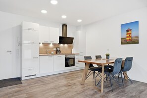 Eine moderne Küche mit weißen Schränken, einer Holz Arbeitsplatte und einem Essbereich mit einem Holztisch und Stühlen.