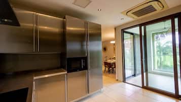 A modern kitchen with stainless steel appliances, a dining area with a table and chairs, and a sliding glass door leading to a balcony.