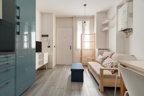 Ein modernes, helles Zimmer mit einer Couch, einem kleinen Tisch, einer Bank und einem Schrank.