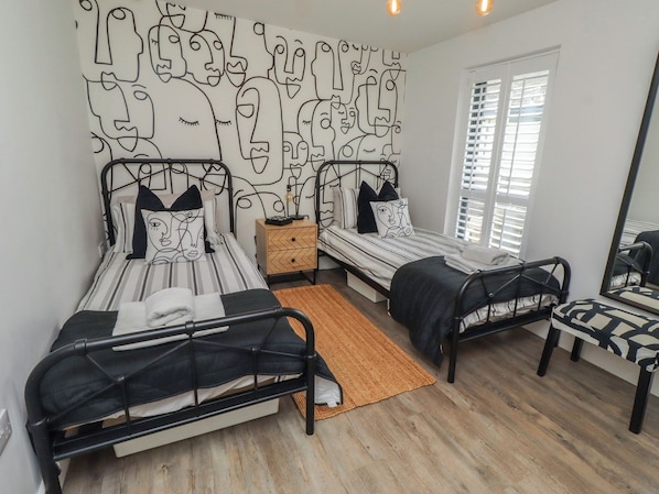 A bedroom with two beds, a nightstand, a chair, and a large mirror.