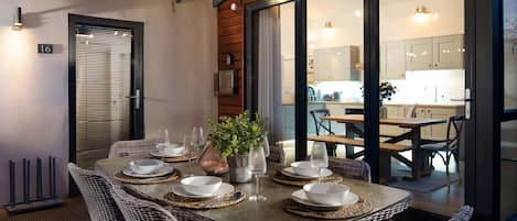 Un área de comedor al aire libre con una mesa dispuesta para seis personas, rodeada de sillas de mimbre.