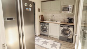A compact kitchen with a built-in washing machine, a microwave, and a refrigerator.