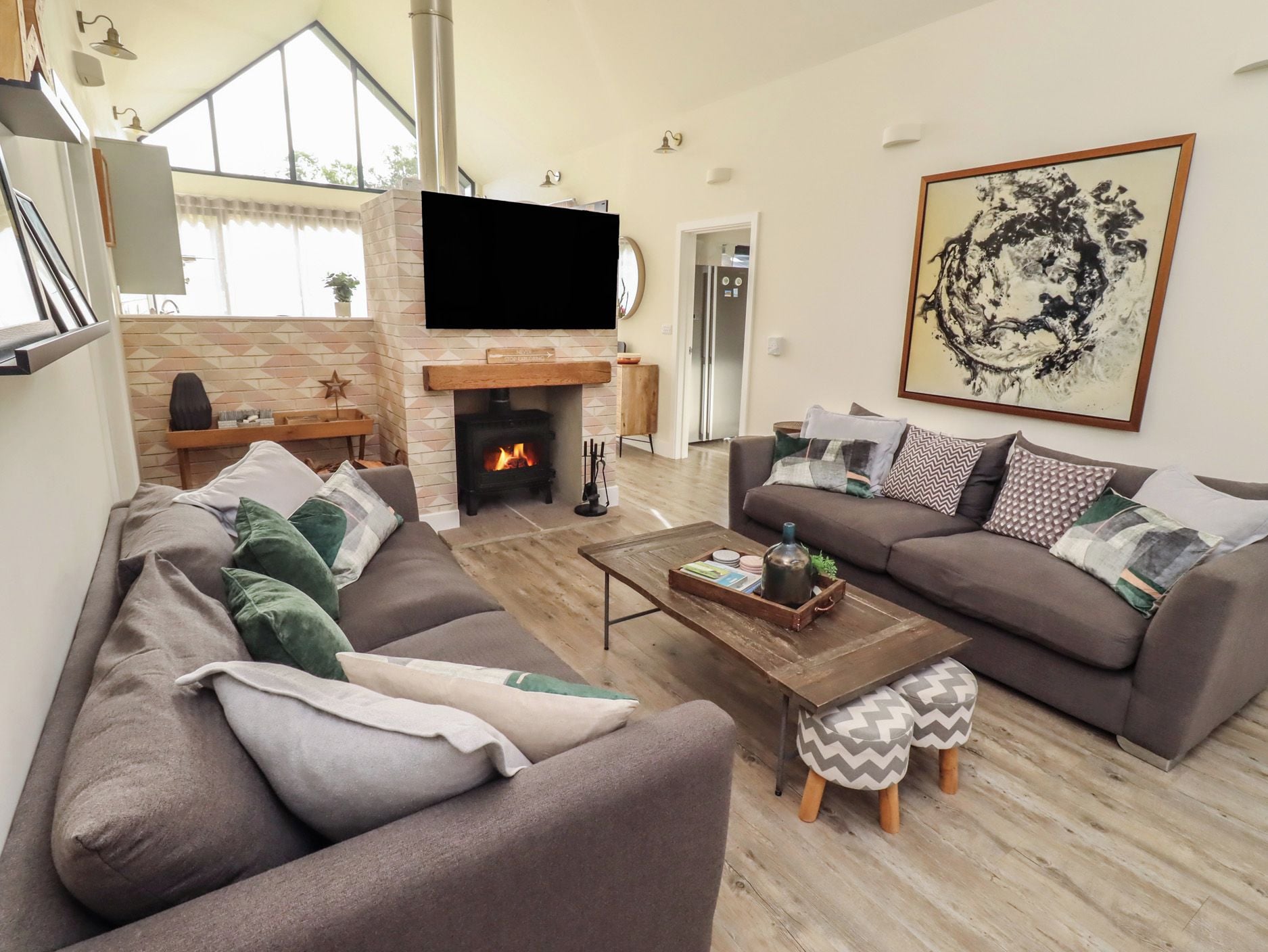 A living room with a fireplace, a sofa set, a coffee table, and a television mounted on the wall.