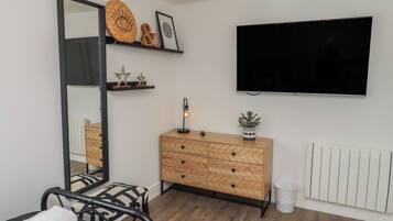 Een moderne kamer met een grote spiegel, een houten dressoir, een flatscreen televisie en een radiator.