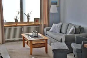 A modern living room with a grey sofa, a wooden coffee table, and a lamp. - Stylish and authentic vacation rental in Friedrichskoog – Perfectly located (Friedrichskoog)