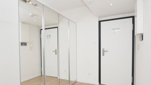 A hallway with a mirrored wardrobe, a door with a black frame, and a light switch on the wall. - The "Kaiserhof 1" vacation rental. (Norderney)