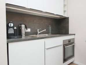 A modern kitchen with a built-in oven, a coffee maker, and a stainless steel sink. - The "Kaiserhof 1" vacation rental. (Norderney)