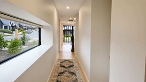 A corridor with a window, a patterned rug, and a door leading to an outdoor area. - Simply Remarkables View in Hanleys |3 bed home (Jack's Point)