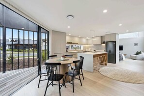 A modern kitchen with a dining area, large windows, and a view of the outside. - Simply Remarkables View in Hanleys |3 bed home (Jack's Point)