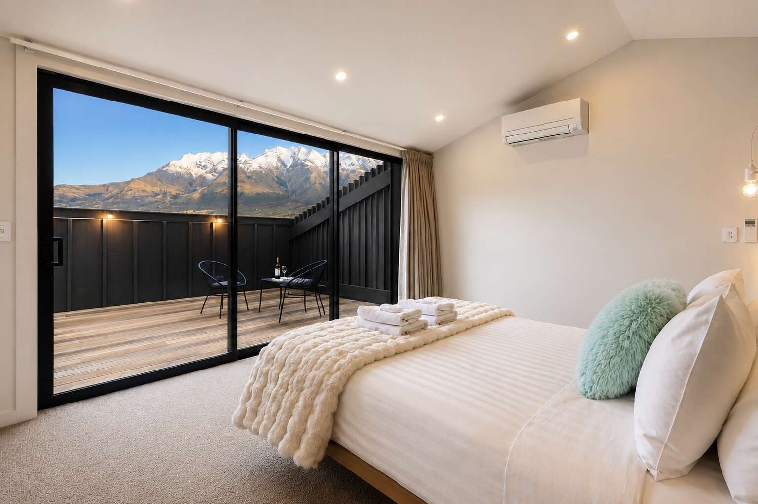Une chambre dotée d’une grande porte-fenêtre coulissante donnant sur un balcon avec vue sur les montagnes.