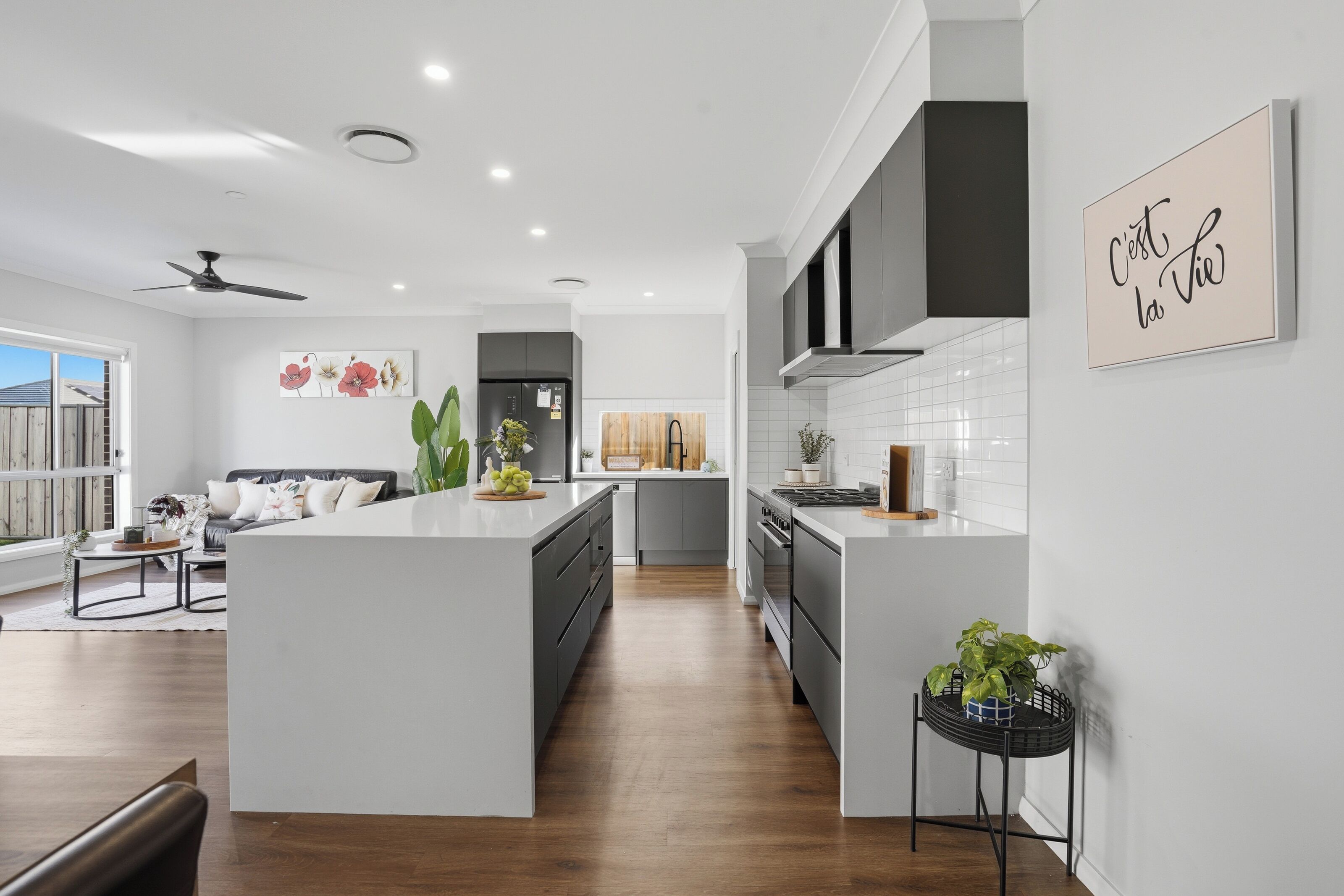 A modern kitchen with a central island, a dining area with a sofa, and a living room with a sofa and a coffee table.