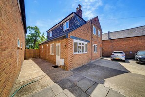 A two-story brick house with a garage, a paved driveway, and a wooden fence. - Cozy 1bed house with free parking (Buckinghamshire)