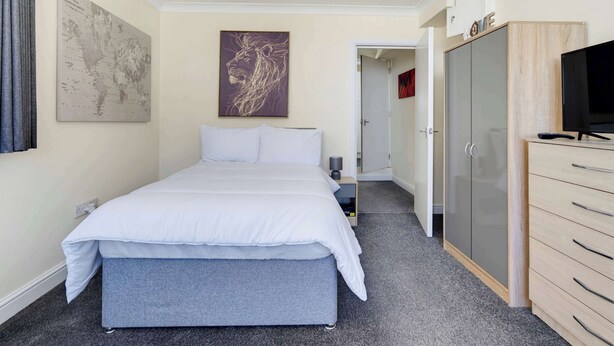 Una habitación de hotel con una cama, un armario, un televisor y un mapa en la pared.
