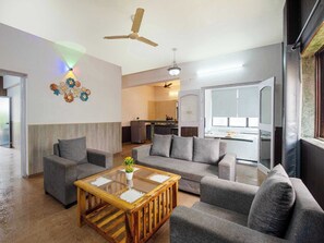 A modern living room with grey sofas, a wooden coffee table, and a ceiling fan. - Palette Mountain Mist 2BHK Jacuzzi (Mawal)