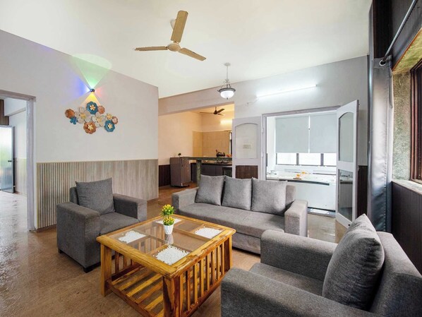 A modern living room with grey sofas, a wooden coffee table, and a ceiling fan.
