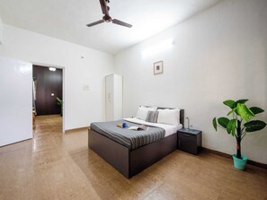 A bedroom with a bed, bedside table, nightstand, and a potted plant. - Palette Mountain Mist 2BHK Jacuzzi (Mawal)
