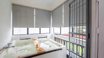 Een balkon met een badkuip, een raam met uitzicht op een rood gebouw en een metalen hek.