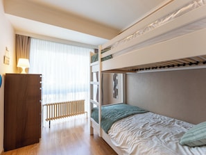 A bunk bed room with a wooden dresser, a radiator, and a window with curtains. - Centrally located Sea You Again by Interhome (Blankenberge)