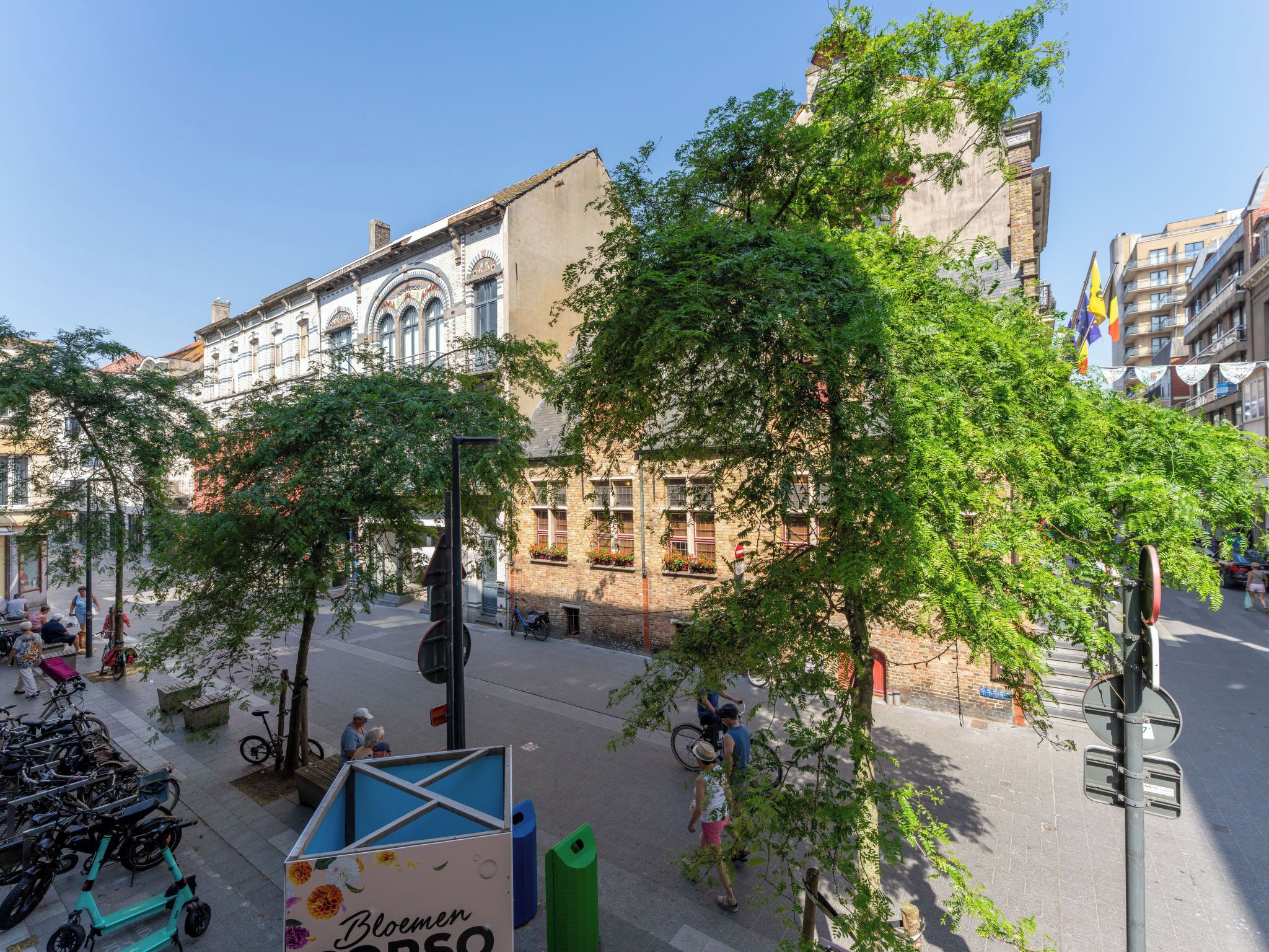 A street with historic buildings, a bicycle lane, and a green trash bin.