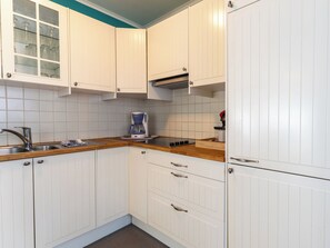 A kitchen with white cabinets, a coffee maker, a sink, and a stove. - Centrally located Sea You Again by Interhome (Blankenberge)