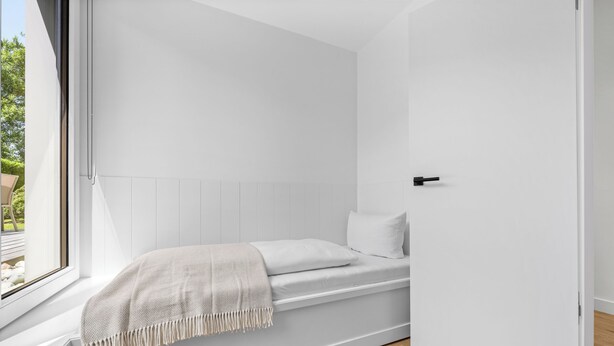 Een minimalistisch ingerichte kamer met een bed, een raam en een deur.