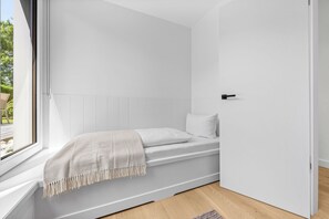 A minimalist room with a bed, a window, and a door. - Arriving between the sea, the light, and the open landscape (List auf Sylt)
